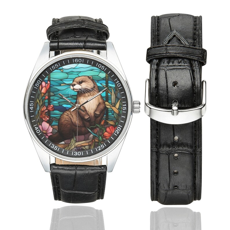 May include: A silver wristwatch with a black leather band. The watch face features a stained glass design of an otter in a blue and green water scene. The numbers on the watch face are in black.