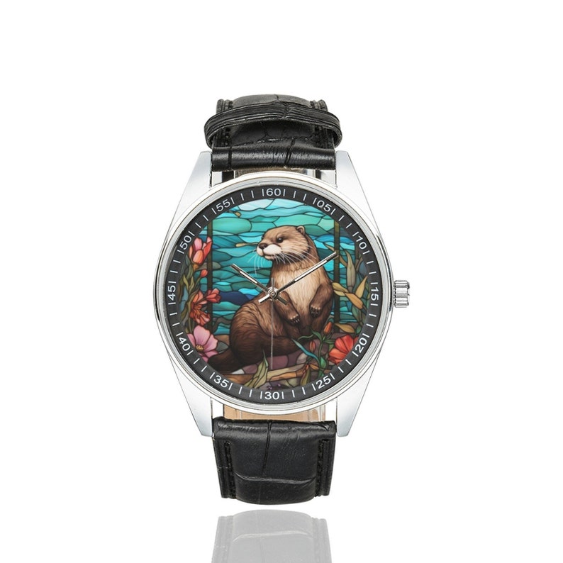 May include: A silver wristwatch with a black leather band. The watch face features a colorful stained glass design of an otter in a blue and green water scene with flowers.