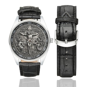 May include: A silver wristwatch with a black leather band. The watch face features a detailed, engraved image of Jesus Christ on the cross. The watch face has Roman numeral markings.