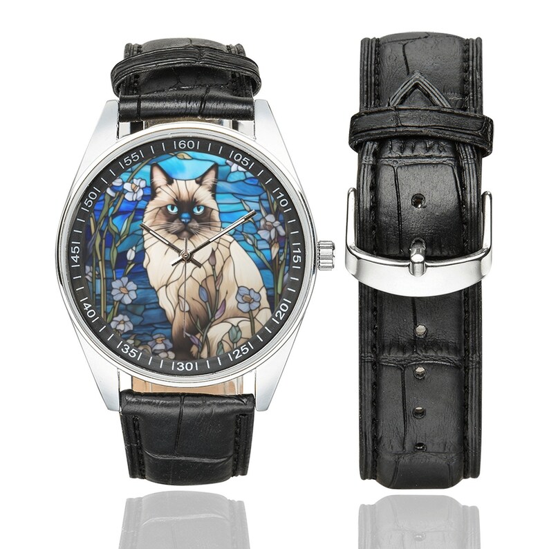 Op de afbeelding: Een zilveren polshorloge met een zwarte leren band heeft een glas-in-loodontwerp van een Siamese kat met blauwe ogen. De wijzerplaat van het horloge heeft zwarte cijfers en markeringen.
