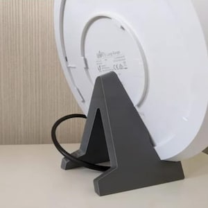 May include: A white, round, wireless router with a gray, triangular stand. The router has the text "Ubiquiti Long Range" printed on the back.