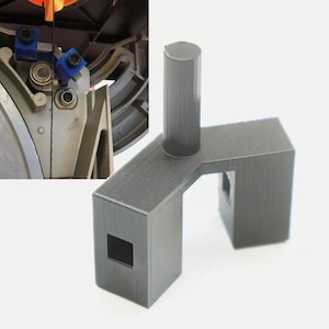 May include: A gray 3D printed tool with a square hole and a cylindrical post. The tool is designed to be used with a saw blade.