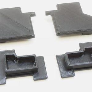 May include: Four black plastic pieces with different shapes and sizes. Some pieces have a rectangular opening.