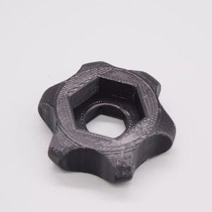 May include: A black plastic star-shaped knob with a hexagonal hole in the center.