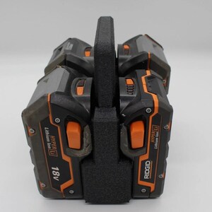 May include: A black and orange power tool battery pack with a black handle. The battery pack has the text "RIDGID" and "18V" printed on it. The battery pack is made of plastic and has a textured surface.