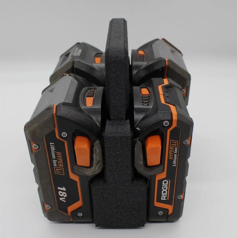 May include: A black and orange power tool battery pack with a black handle. The battery pack has the text "RIDGID" and "18V" printed on it. The battery pack is made of plastic and has a textured surface.