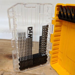 May include: A clear plastic storage case with a yellow lid, containing a set of small metal blades. The case has the word "DEWALT" printed on the side.