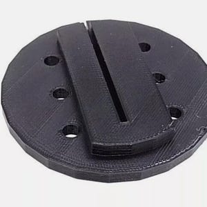 May include: Black plastic circular base with multiple holes and a black plastic insert with a slot in the center.