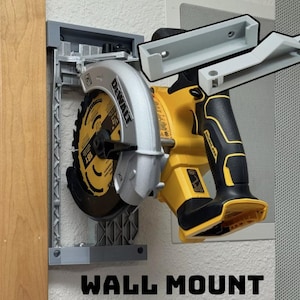 May include: A gray wall mount for a circular saw. The saw is yellow and black with a silver blade. The wall mount has the text "WALL MOUNT" printed on it.