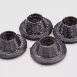 May include: Four black plastic caps with a raised lip around the edge. The caps are designed to fit over a round object.