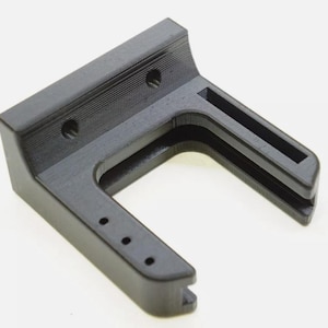 May include: A black plastic 3D printed wall mount with a U-shaped opening. The mount has several small holes for mounting screws.