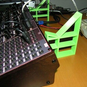 May include: A black and red electronic music synthesizer with a large number of knobs and buttons. The synthesizer is sitting on a green plastic stand.