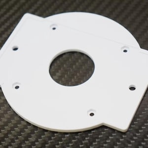 May include: White plastic mounting plate with a circular cutout in the center and several screw holes around the edge.