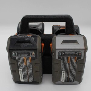 May include: A black and gray Hyper Lithium Ion battery charger with a black handle. The charger has two battery slots and includes text that reads "PACK CHARGING RANGE" and "PACK RECHARGE GAMME".