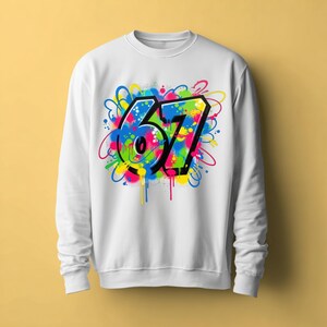 Pu&ograve; includere: Felpa bianca con un design in stile graffiti. Il design presenta il numero "67" in nero, delineato da un vivace mix di schizzi e gocce di vernice blu, verde, giallo, rosa e arancione.