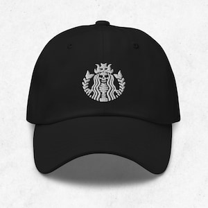 Puede incluir: Gorra de béisbol negra con un diseño bordado en blanco. El diseño es una calavera coronada, rodeada por una corona de laurel, que se asemeja a un logotipo de cafetería popular. La gorra tiene una visera curva y una correa ajustable.
