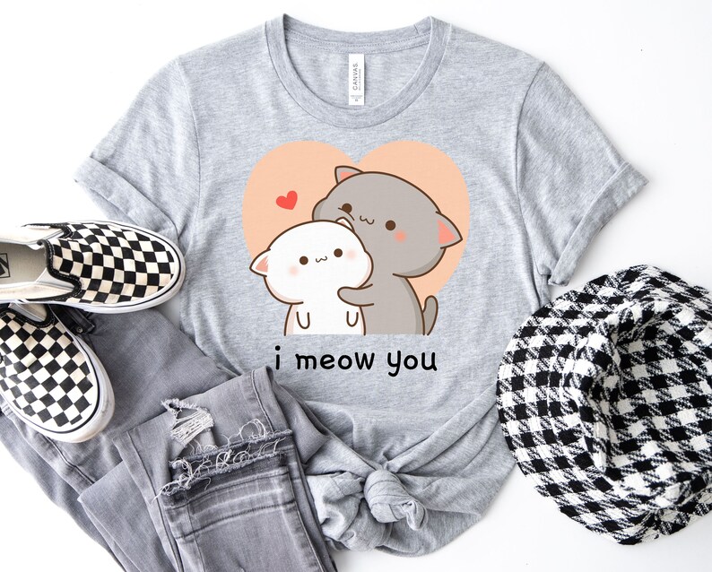 K&ouml;nnte beinhalten: Graues T-Shirt mit einem Cartoon-Bild von zwei Katzen, die sich in einem Herzen umarmen. Der Text "i meow you" ist unter dem Bild gedruckt.
