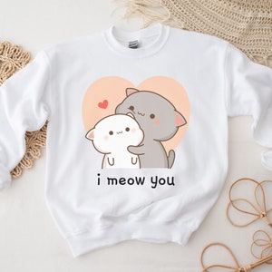 K&ouml;nnte beinhalten: Wei&szlig;er Pullover mit einem Aufdruck von zwei kuschelnden Comic-Katzen in einem Herzen. Der Text "i meow you" ist unter den Katzen aufgedruckt.