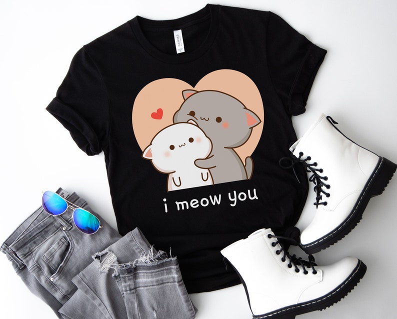 K&ouml;nnte beinhalten: Schwarzes T-Shirt mit einem Motiv von zwei Karikaturkatzen, die sich in einem Herzen umarmen. Der Text "i meow you" ist unter den Katzen gedruckt.