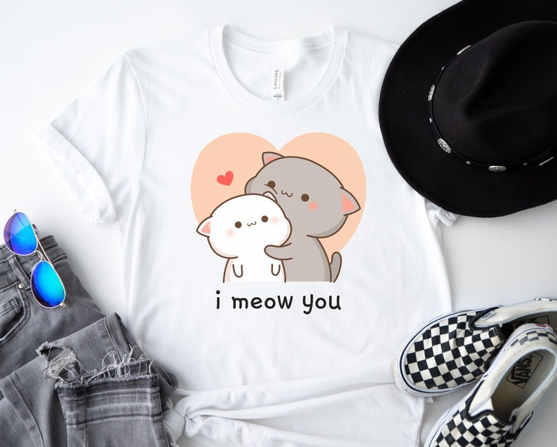 K&ouml;nnte beinhalten: Wei&szlig;es T-Shirt mit einem Cartoon-Bild von zwei Katzen, die sich in einem Herzen umarmen. Der Text "i meow you" ist unter dem Bild gedruckt.