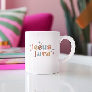 Puede incluir: Taza de cerámica blanca con el texto "Jesus Java" en letras retro de colores y pequeños acentos de estrellas.