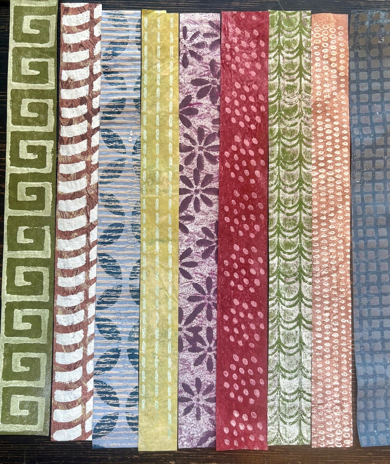 May include: A collection of ten rectangular paper strips with various patterns and colors. Designs include geometric shapes, floral patterns, and dotted textures. Colors range from green, brown, and blue to yellow, purple, and red.