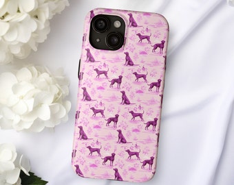 May include: A pink phone case with a repeating pattern of purple dogs. The case has a cutout for the camera lens.