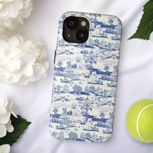 May include: A white iPhone case with a blue and white pattern of dogs, trees, and houses. The case has a camera lens cutout on the back.
