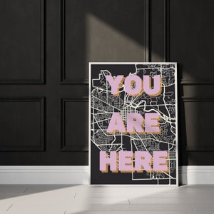 May include: A black and white city map print with the words "YOU ARE HERE" in pink and gold letters.