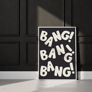 Pu&ograve; includere: Un poster in bianco e nero con la parola "BANG!" ripetuta tre volte in un carattere divertente e di grandi dimensioni.