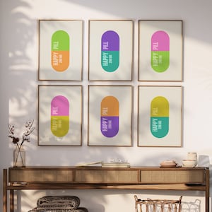 May include: Six framed prints with a minimalist design featuring a pill shape with the text "Happy Pill" and "200 MG" in a colourful palette of green, yellow, purple, pink, and teal.