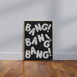 Pu&ograve; includere: Un poster incorniciato nero con la parola "BANG!" ripetuta in bianco, con caratteri stilizzati.