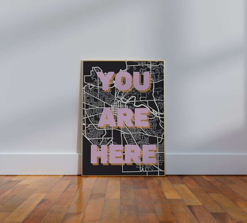 May include: A black and white map with a gold frame. The words "YOU ARE HERE" are written in pink on the map.