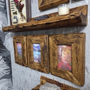 May include: A wooden shelf with a candle and decorative items, and three framed landscape prints. The frames and shelf have a natural, rough-hewn appearance, adding a touch of nature-inspired decor. The prints depict scenic views.