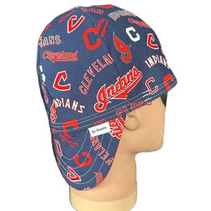 May include: Blue and red baseball cap with a pattern of the Cleveland Indians logo. The cap has a flap that can be worn down to protect the neck and ears. The cap has a label that says "Bo-Beanies".