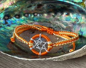 May include: Orange and white braided bracelet with a small silver dreamcatcher charm.