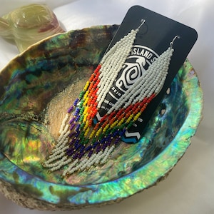 May include: Rainbow beaded earrings with white beads and gold accents. The earrings are displayed on a black card with the text "Island Soul" and "Made in the US. Owned & Operated by Island Soul Co."