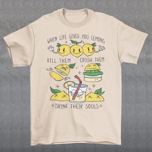 Introducing our adorable and quirky Lemonade-themed t-shirt that is sure to turn heads and bring a smile to your face! This shirt features a delightful design showcasing cute lemons being transformed into delicious lemonade, accompanied by the bold, tongue-in-cheek text: "WHEN LIFE GIVES YOU LEMONS, KILL THEM, CRUSH THEM AND DRINK THEIR SOULS."