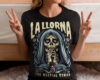 Könnte beinhalten: Schwarzes T-Shirt mit einem Grafikdruck einer weinenden Frau mit einem Schädelgesicht. Der Text "La Llorna The Weeping Woman" ist unter dem Grafikdruck aufgedruckt.