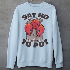 Puede incluir: Sudadera azul claro con un langostino de dibujos animados en una olla y el texto "SAY NO TO POT".