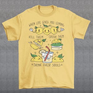 Introducing our adorable and quirky Lemonade-themed t-shirt that is sure to turn heads and bring a smile to your face! This shirt features a delightful design showcasing cute lemons being transformed into delicious lemonade, accompanied by the bold, tongue-in-cheek text: "WHEN LIFE GIVES YOU LEMONS, KILL THEM, CRUSH THEM AND DRINK THEIR SOULS."