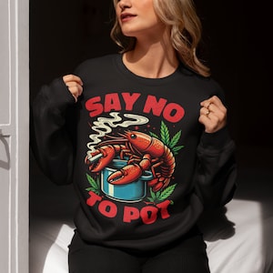 May include: Black sweatshirt with a red lobster holding a cigarette and sitting in a blue pot. The text "SAY NO TO POT" is printed in red on the sweatshirt.