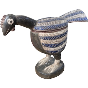 Puede incluir: Figura de pájaro de madera tallada a mano con tapa con bisagras. El pájaro está pintado de negro, blanco y azul, con un patrón de plumas detallado en el cuerpo y la cola. La figura se apoya sobre una base oscura y tiene una cabeza detallada.