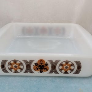 May include: White square baking dish with a brown and orange geometric pattern around the rim.