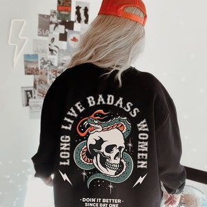 May include: Black sweatshirt with a graphic print of a skull with a snake wrapped around it. The text "Long Live Badass Women" is printed in a circle around the skull. The text "Doin' it better. Since day one." is printed below the graphic.