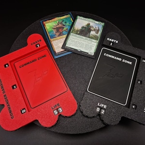 Puede incluir: Dos bandejas de juego de plástico rojo y negro para jugar a Magic: The Gathering. Cada bandeja tiene una zona de mando, un contador de vida y una sección para hacer un seguimiento de los daños de comandante infligidos. La bandeja roja tiene un total de vida de 53 y la bandeja negra tiene un total de vida de 02.