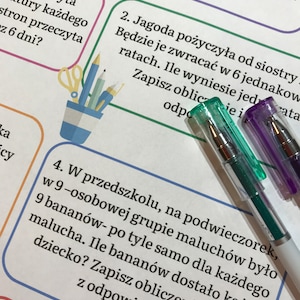 May include: A close-up of a worksheet with Polish text and colorful borders. Two gel pens with clear caps are in the foreground. The pens are green and purple. A small illustration of pencils and scissors is visible.