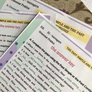 May include: Close-up of several printed ESL grammar practice worksheets for B1-level teenagers. The worksheets feature fill-in-the-blank exercises on past simple and continuous tenses. The text "the answer key" is visible. The background includes a patterned fabric.