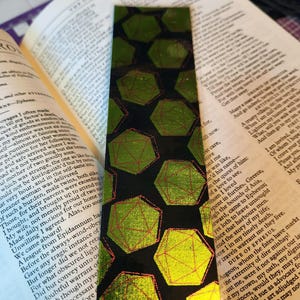 May include: A black bookmark with a geometric pattern of green and red hexagons. The hexagons are outlined in red and filled with a gradient of green.