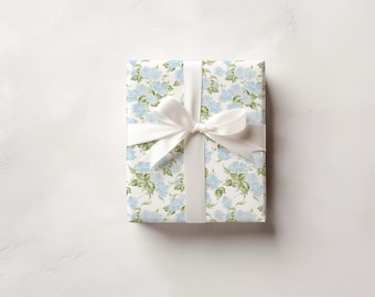 May include: A white gift box with a blue and green floral pattern and a white satin ribbon.